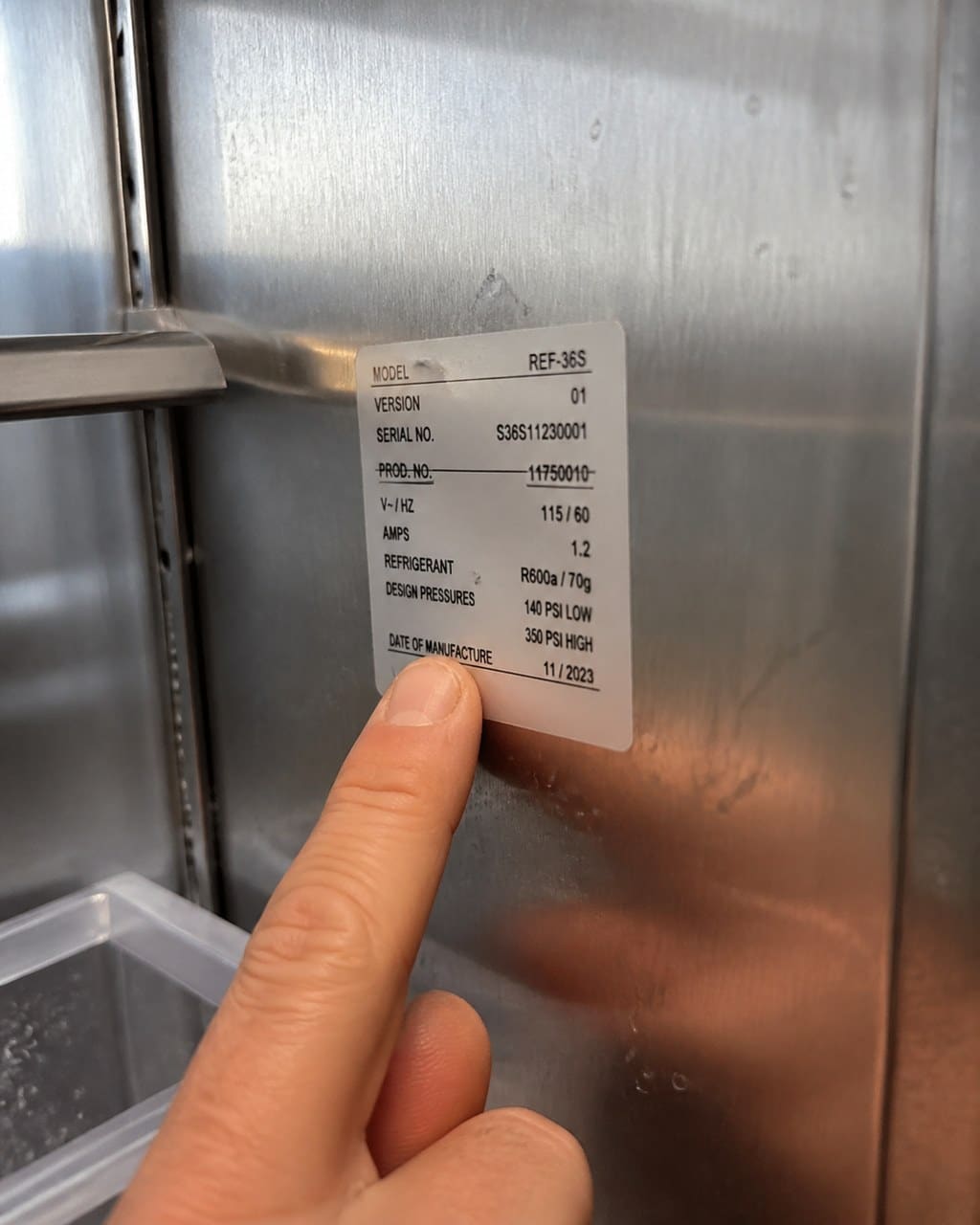 Technician pointing to the model and serial sticker inside a Sub-Zero cabinet